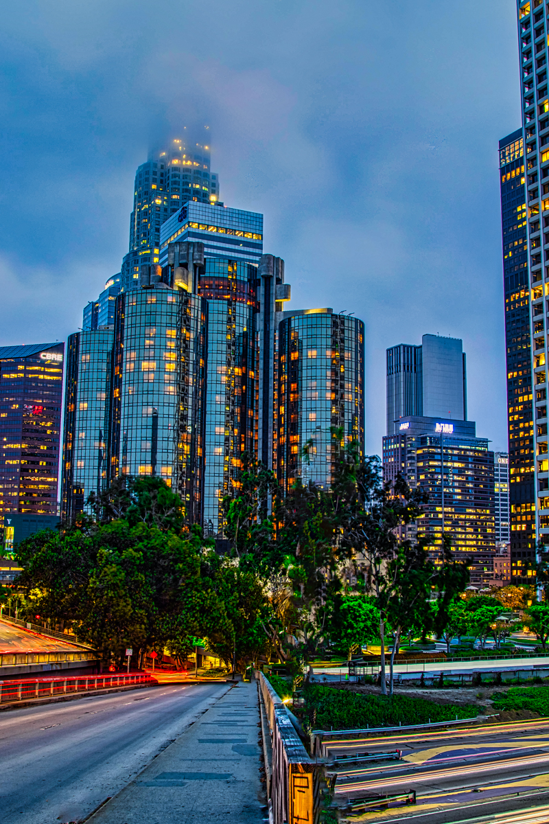 Downtown LA towers at blue hour — light streaks on the 110 freeway below